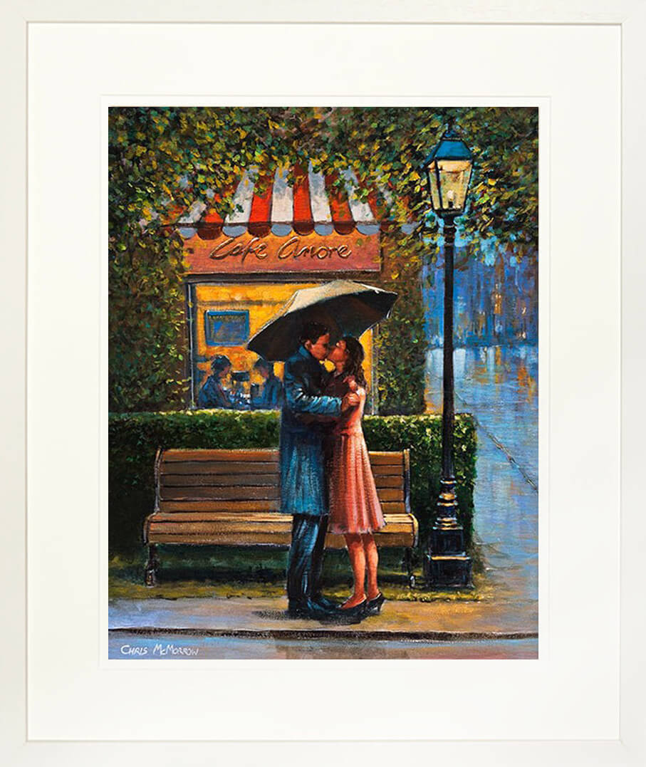 A framed print of a painting of a couple in a romantic embrace by a Parisien cafe