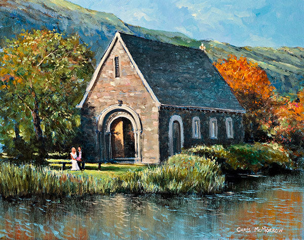 An acrylic painting of the pretty stone church at Gougane Barra, Co Cork, a couple sit on a bench in the foreground.
