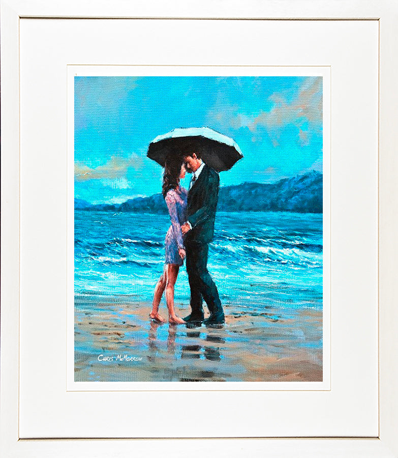 A framed print of a seascape painting of two lovers together under an umbrella on the strand